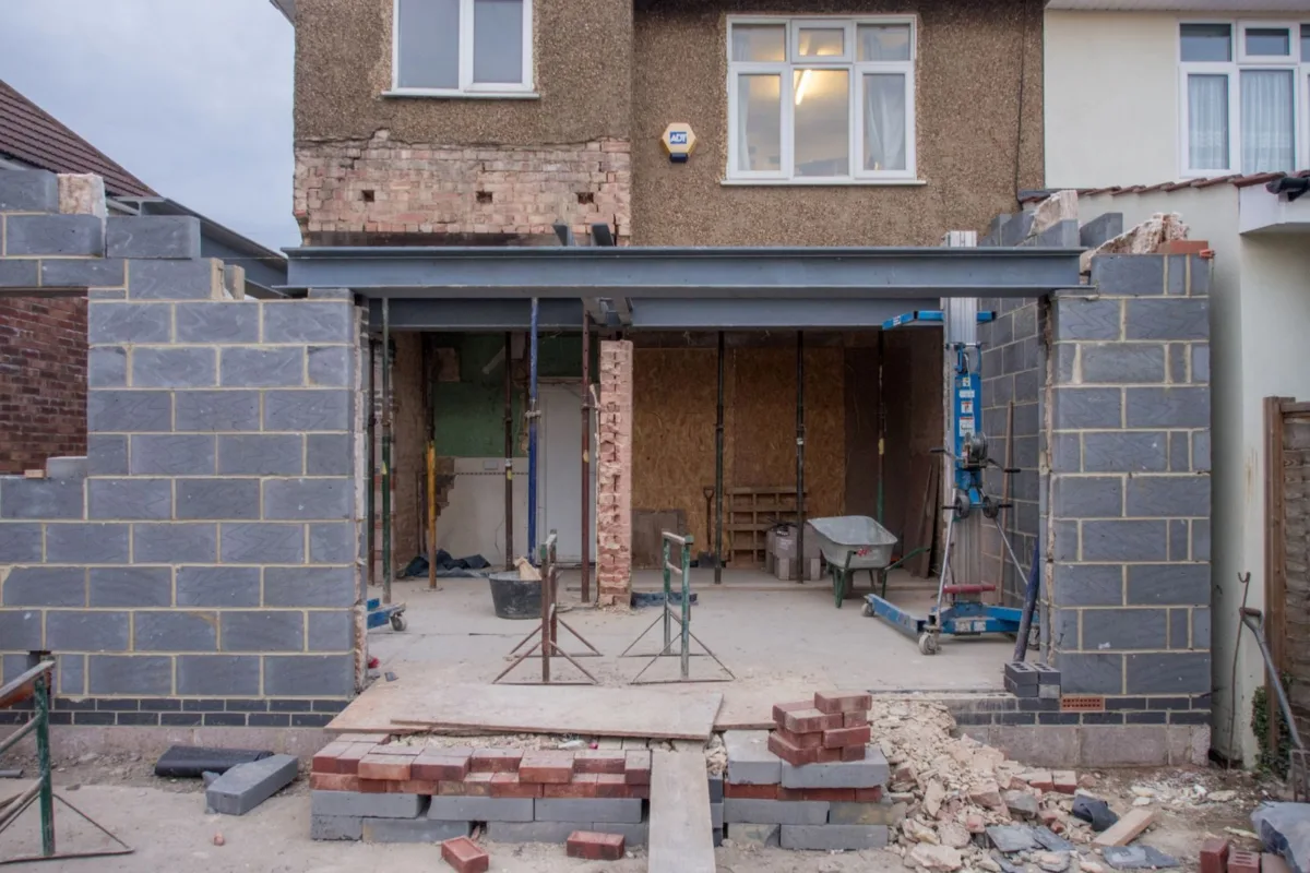 Extension en cours de montage sur une maison existante, ossature et charpente visibles