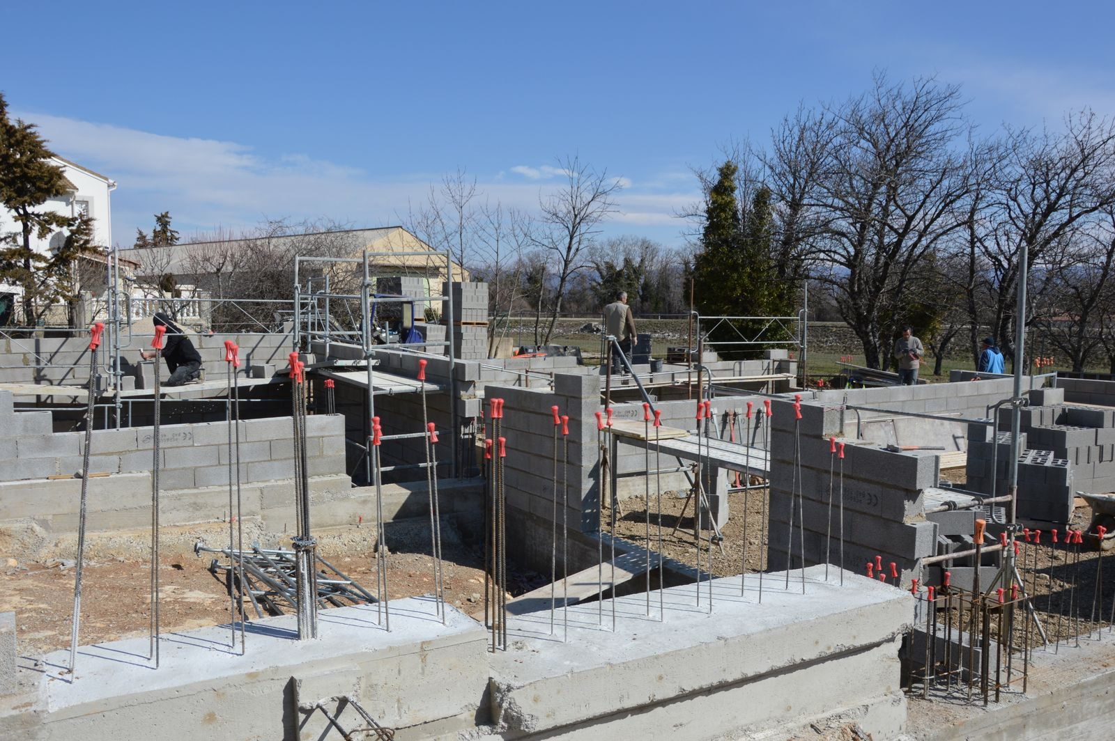 Ouvriers coulant une fondation beton sur un chantier, poste cle d'une maison conteneur en sol argileux