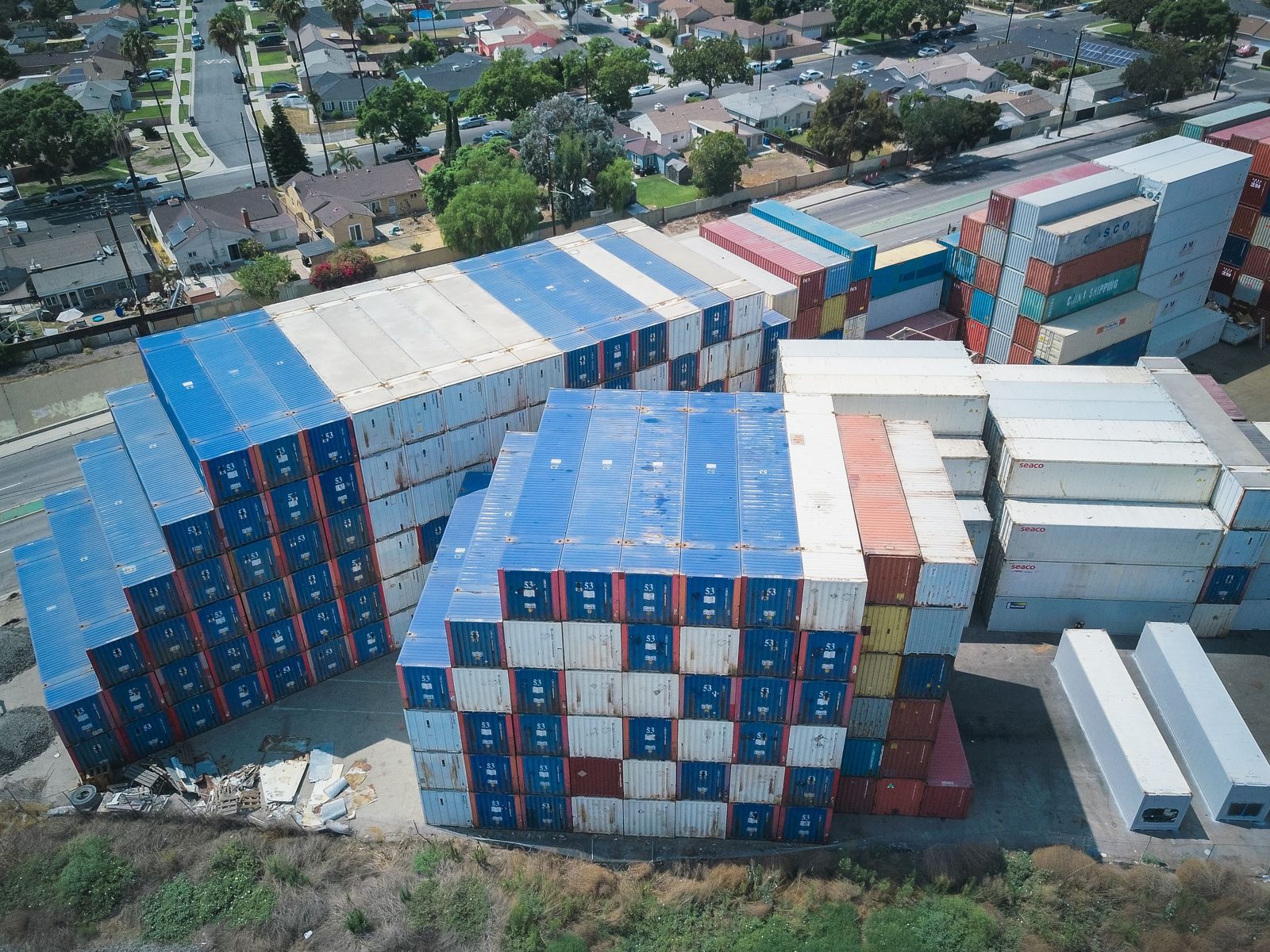 Conteneurs maritimes empilés près de logements, vue aérienne