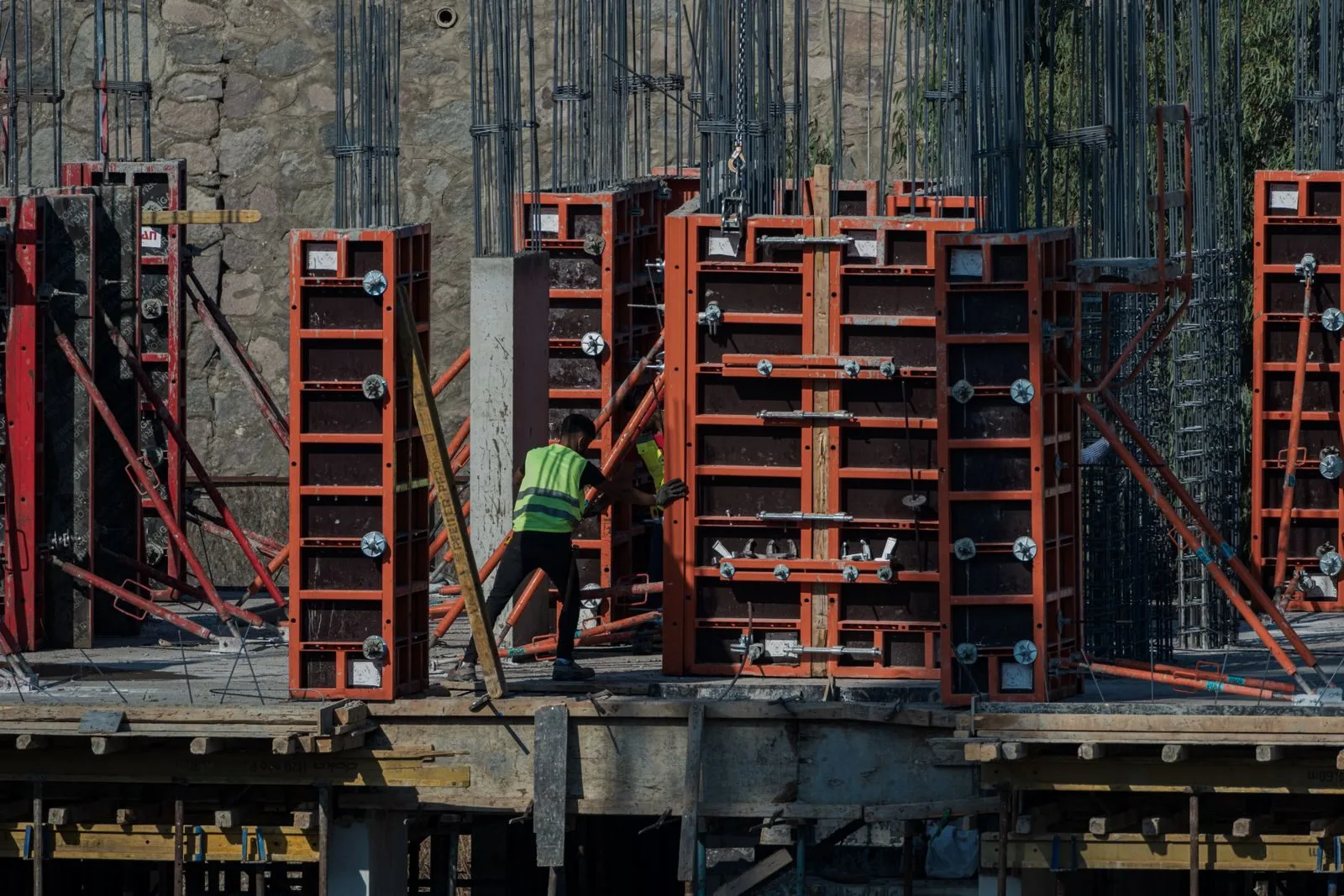 Ouvrier sur un chantier devant une ossature de coffrage pour mur en béton